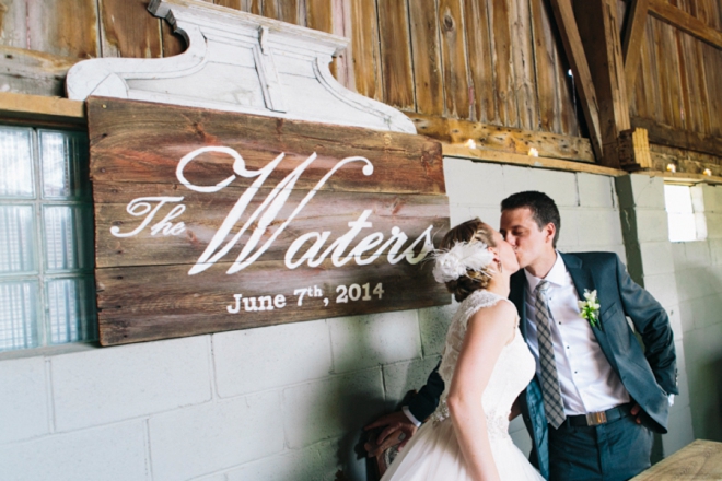 Kissing in front of hand painted wedding sign