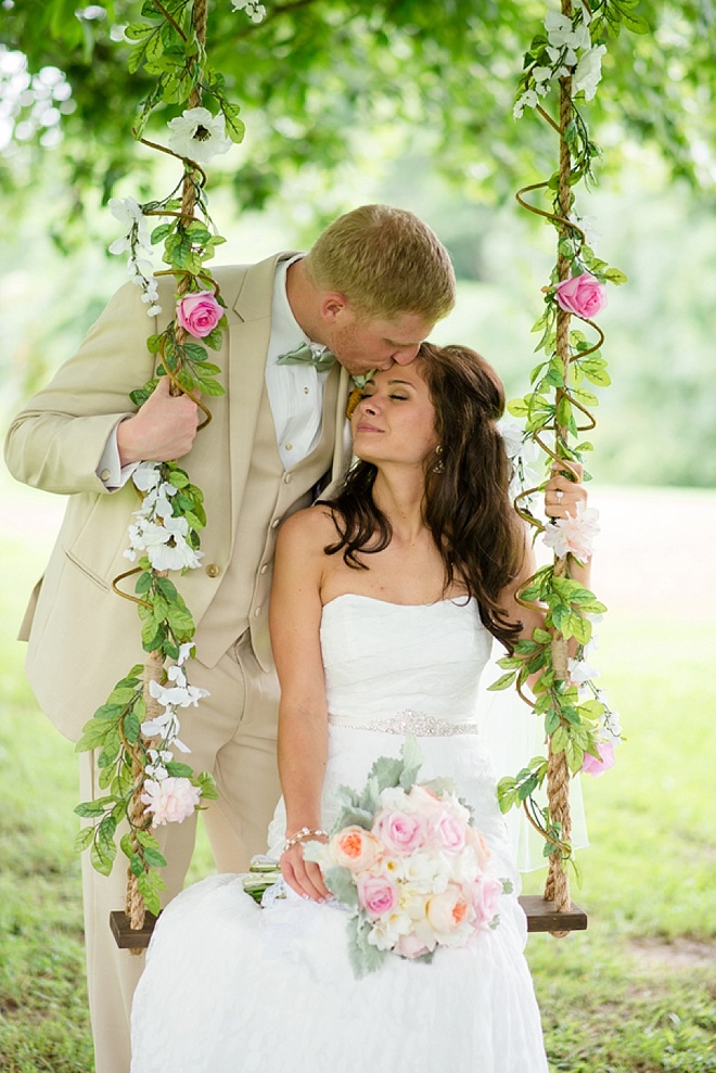 bride and groom kiss on a swing