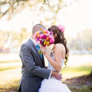 Bride and groom kissing behind flowers
