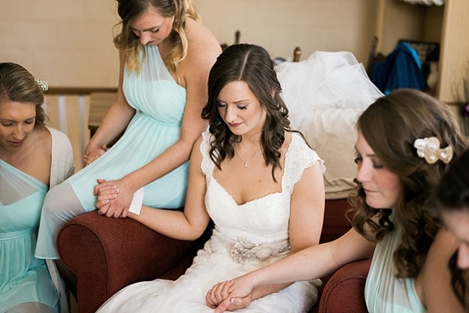 Bride praying with her bridesmaids