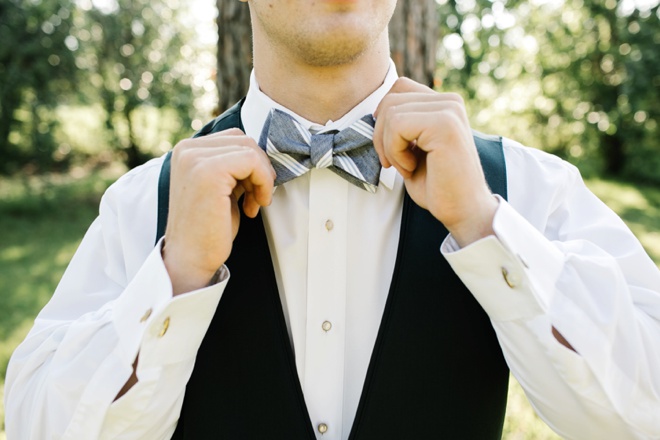 Groom fixing his bow tie.