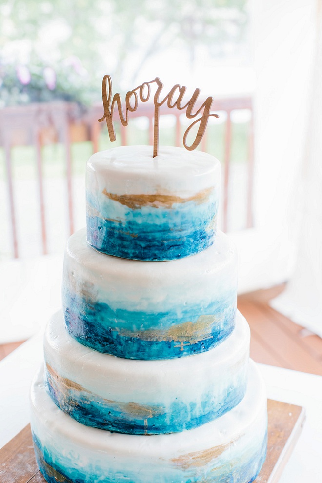 We're swooning over this handpainted blue wedding cake and darling hooray cake topper!
