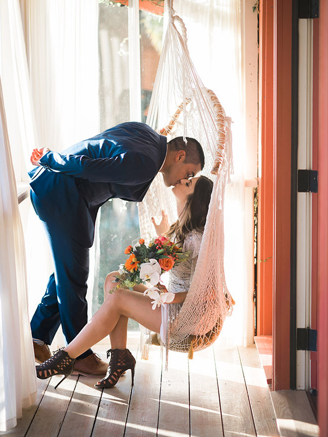 Gorgeous shot of a groom kissing his bride in a swing chair!
