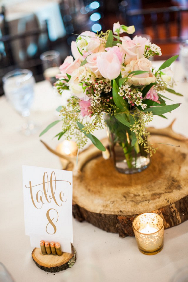 We're loving these handcut wooden centerpices and gold hand lettered table numbers held by bullet casings!