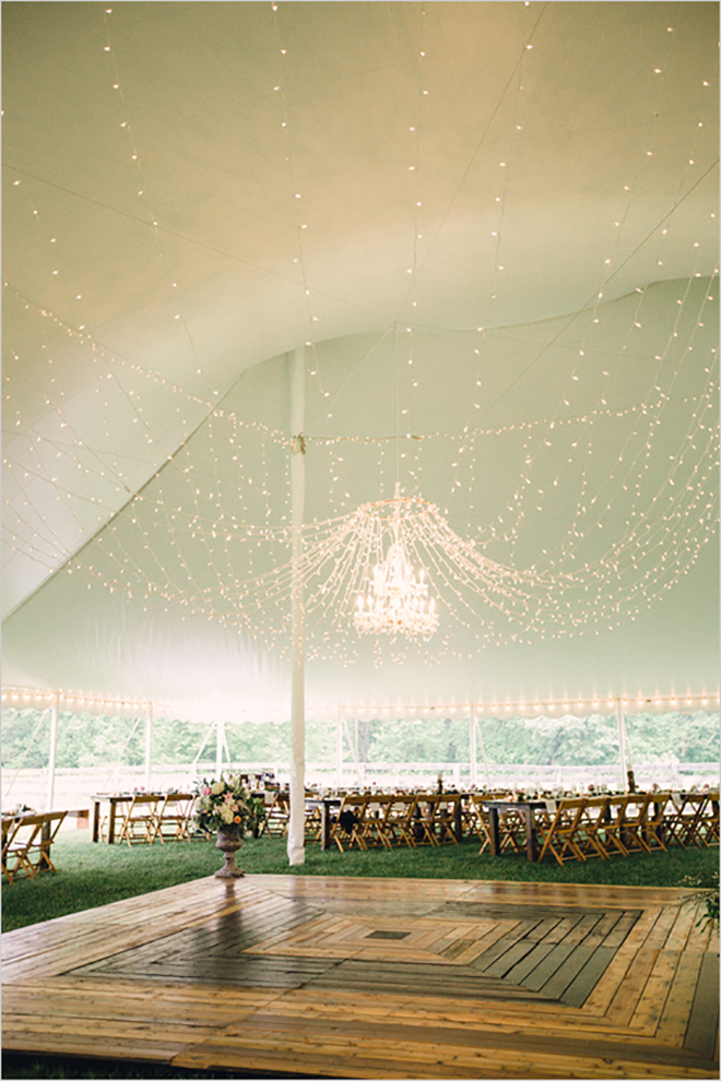 twinkle lights and a wired chandelier sets the mood in a wedding tent