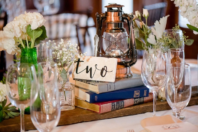 We love these book and greenery centerpieces at these teacher's lakeside wedding!