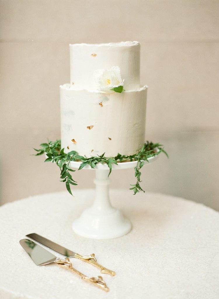 There's something special about this minimalist wedding cake with gold flecks and greenery. So classic.